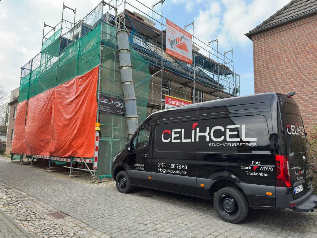 ein Haus mit einem Gerüst, es wird mit Mineralwolle gedämmt. Davor steht ein schwarzer Transporter vom Stuckateurbetrieb Celikcel in Kleve